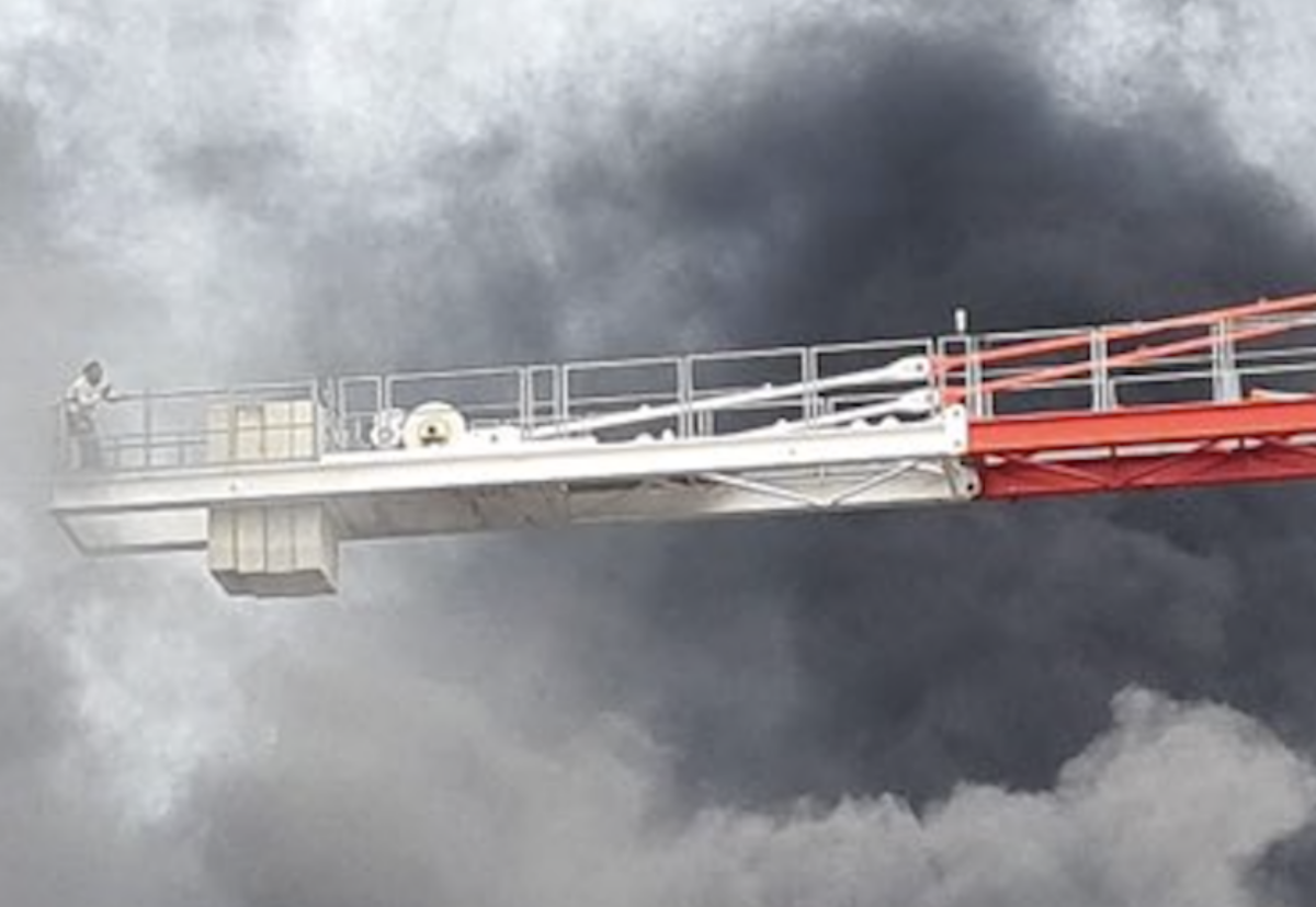 Man perched at the end of crane counter jib to escape thick smoke engulfing site crane